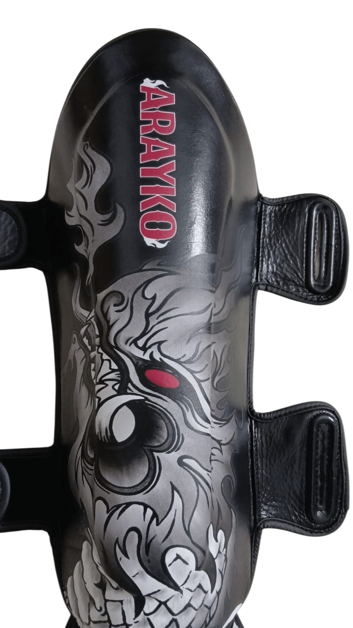 Black combat sports shin guard with traditional gray Asian dragon breathing fire and vertical red ARAYKO branding for striking contrast