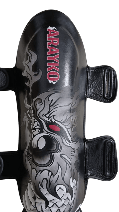 Black combat sports shin guard with traditional gray Asian dragon breathing fire and vertical red ARAYKO branding for striking contrast