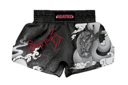 Custom black Muay Thai shorts with a large grey dragon and cloud design. The left side features bold red "Muay Thai" lettering in a stylized font, showcasing traditional combat sports apparel aesthetics.
