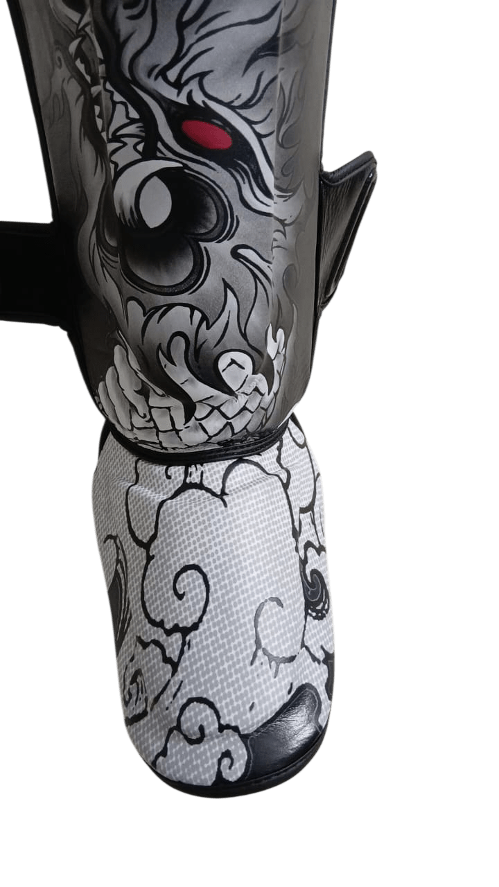 Black shin guard in authentic thai leather, featuring an angry Thai Naga dragon head and mouth with red eyes emerging from clouds UV printed on the foot protection