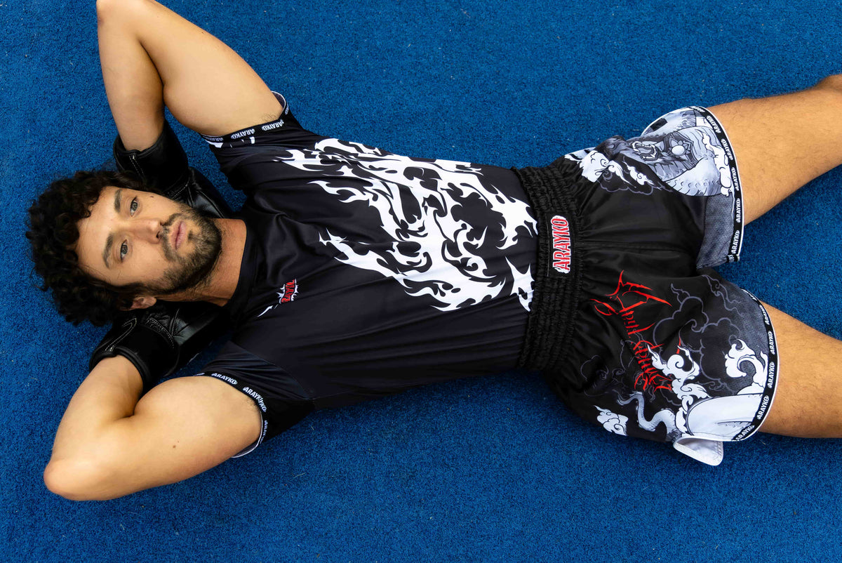 Professional martial artist wearing ARAYKO brand Muay Thai gear and lightweight shorts during a workout break.