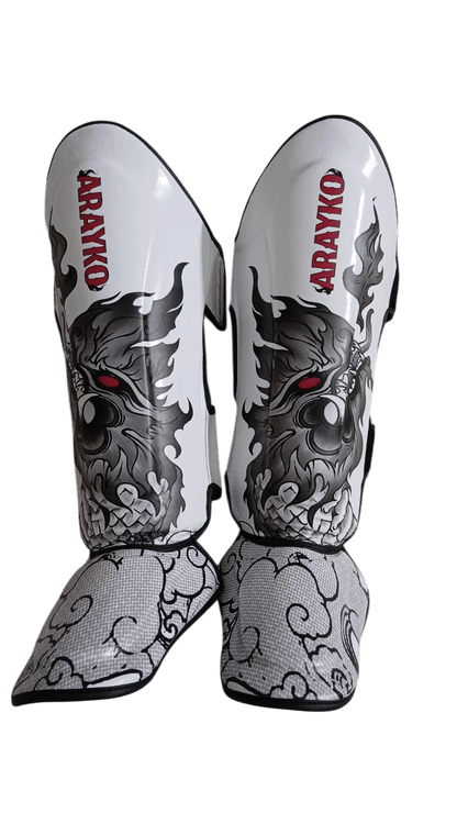 Pair of white leather shin guards with black thai dragon design and 'ARAYKO' branding on a transparent background.