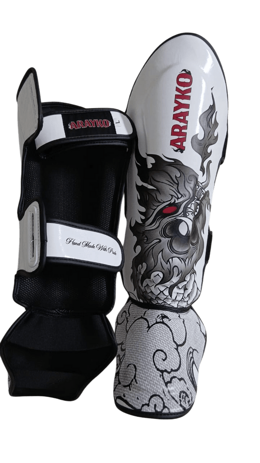 Durable protective shin pads by ARAYKO, white with gray dragon print, adjustable straps, ideal for sparring and kickboxing workouts